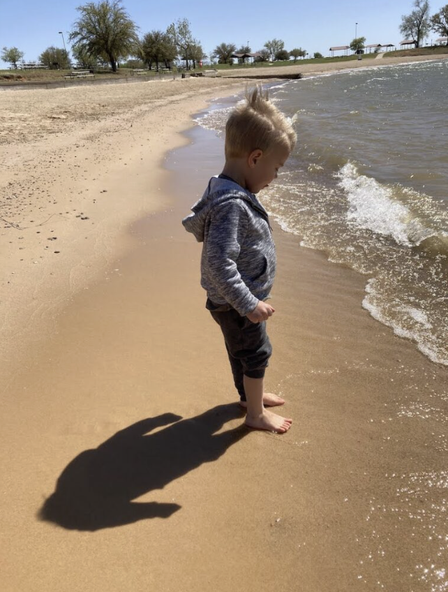 a young boy on the beach at a lake