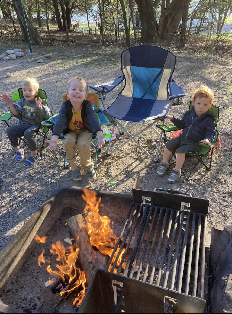 3 boys in camp chairs by a campfire