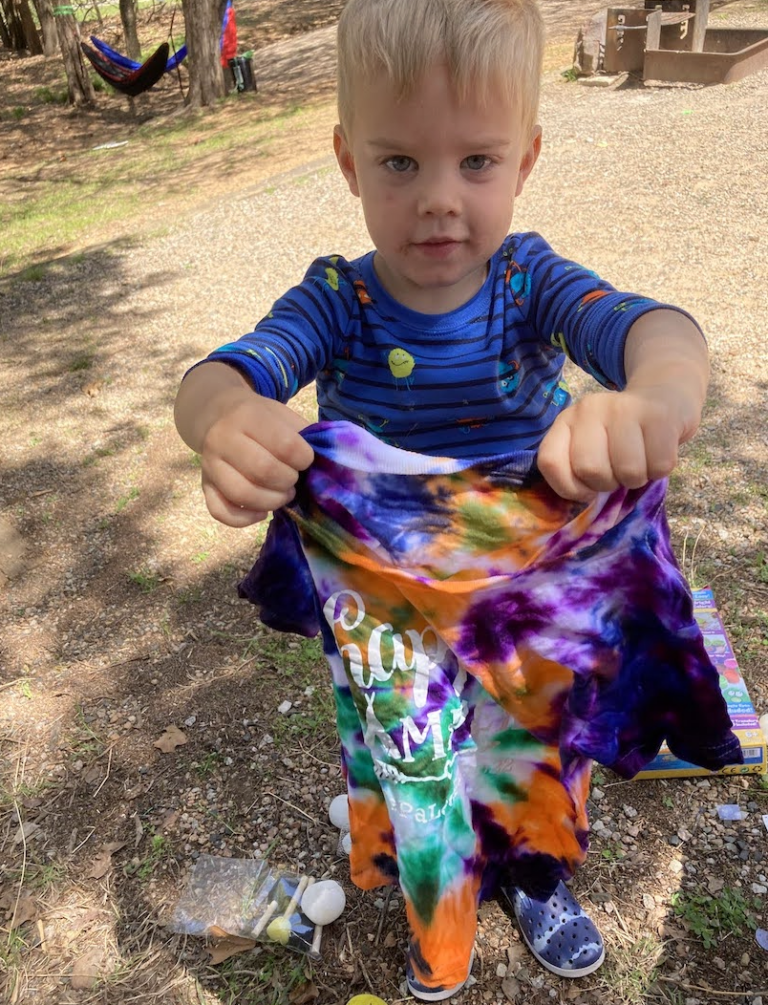 A boy holding a tie dyed shirt