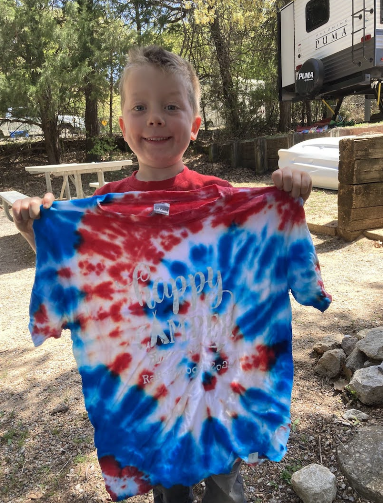 a boy holding a tie dyed shirt