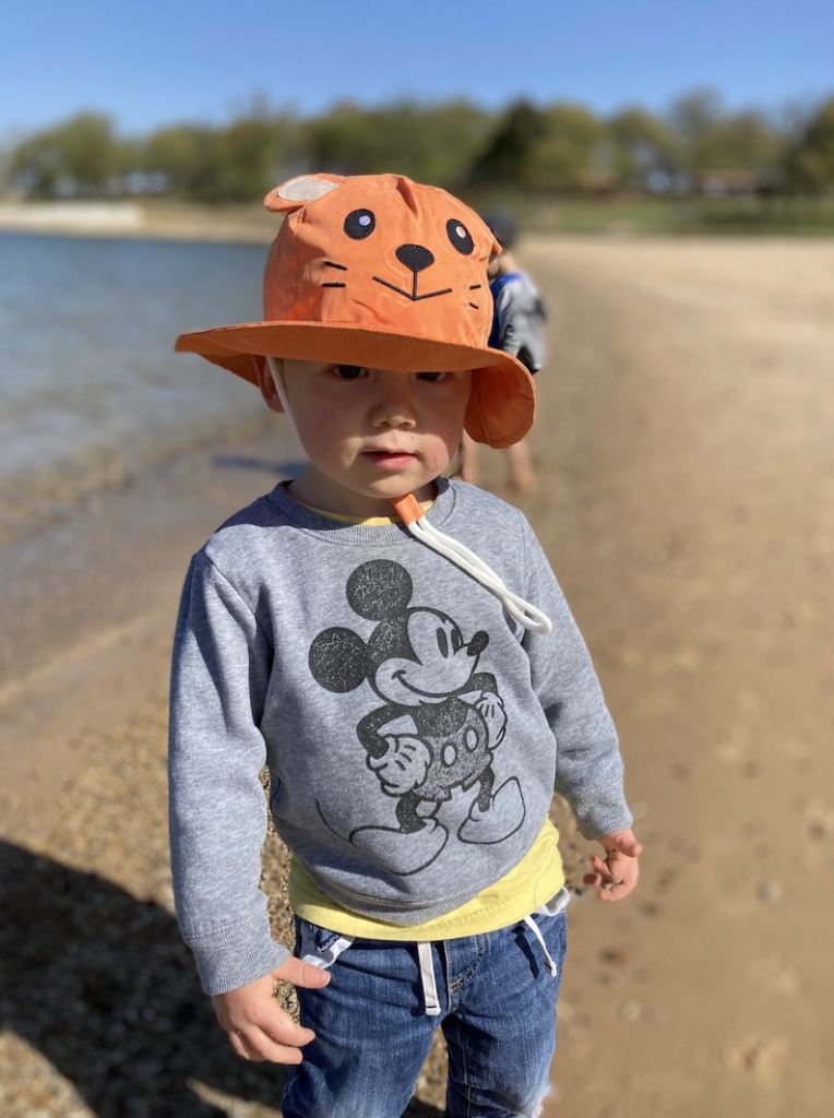 a little boy at the lake wearing an orange hat