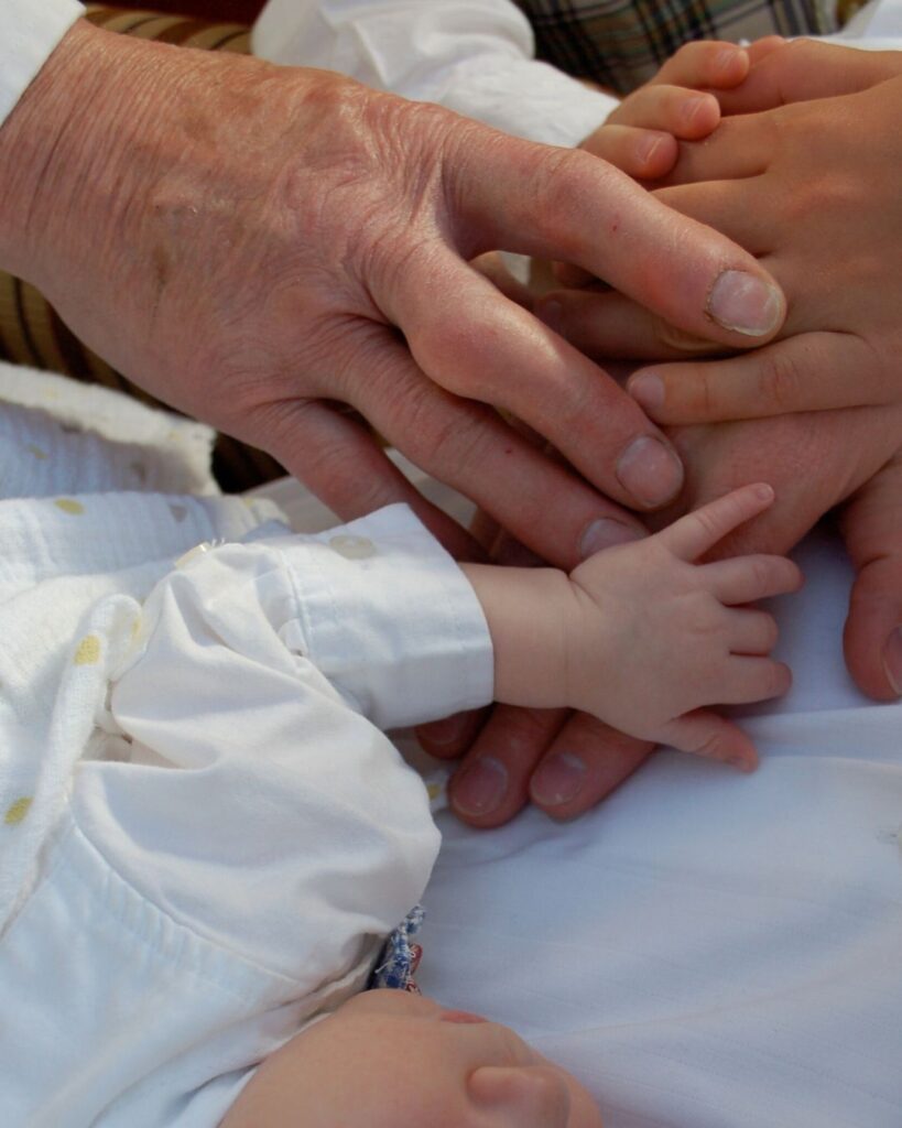 Grandfather's hands next to infant's hands