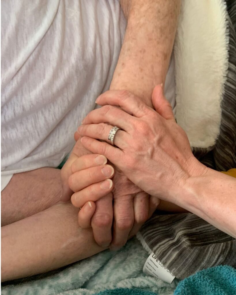 woman's hands holding an elderly man's hand