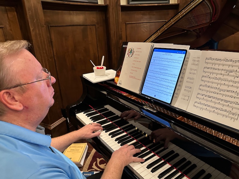 man playing a piano with music on an iPad