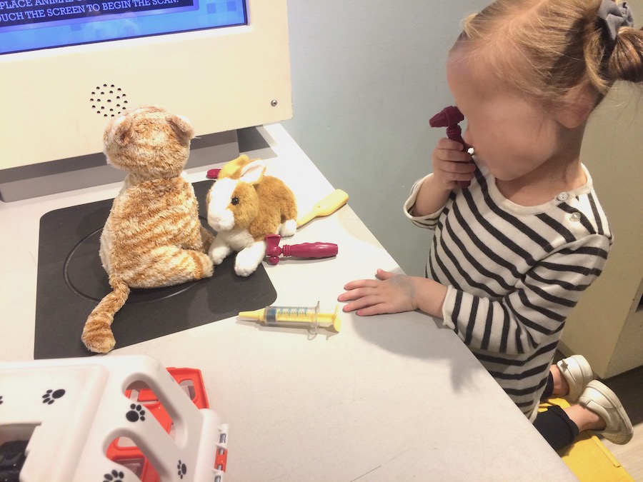 child examining stuffed toys with pretend docor kit