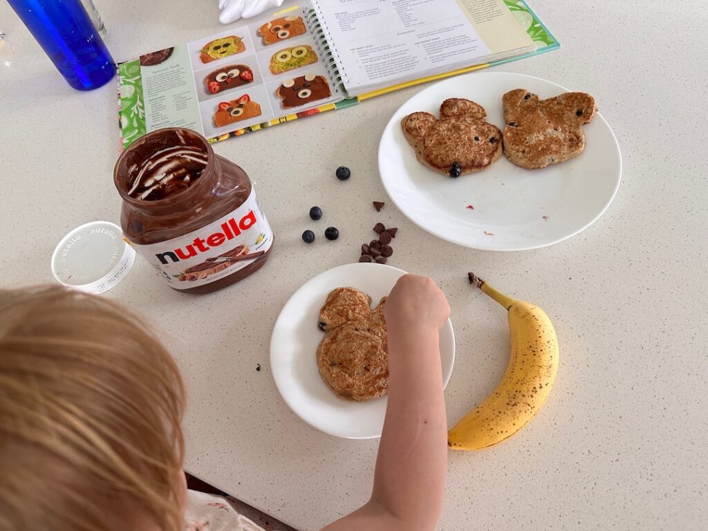 child decorating bear-shaped pancakes