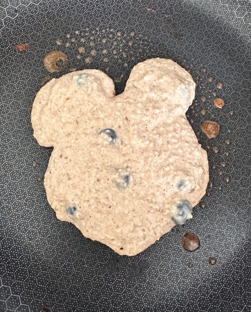 bear-shaped pancake cooking in a skillet