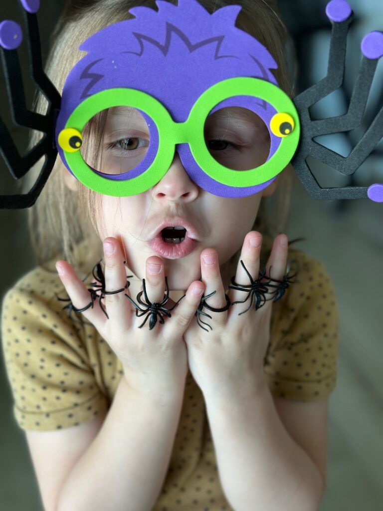 girl wearing spider glasses with plastic spiders on her fingers