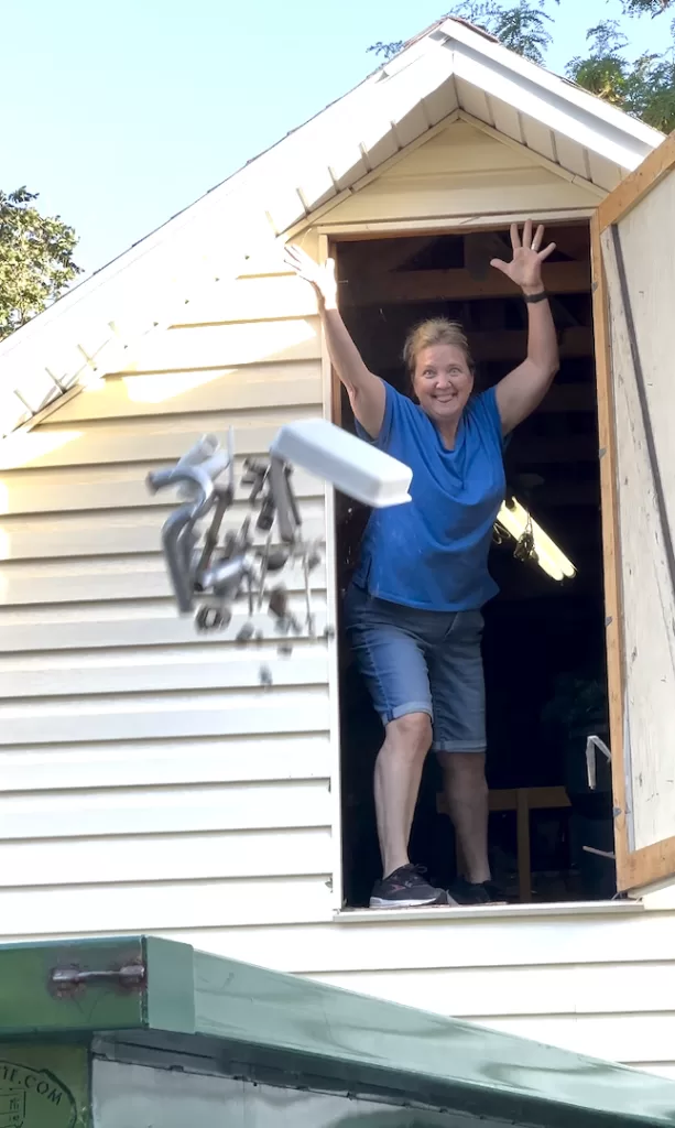 Marilee throwing plumbing parts into dumpster