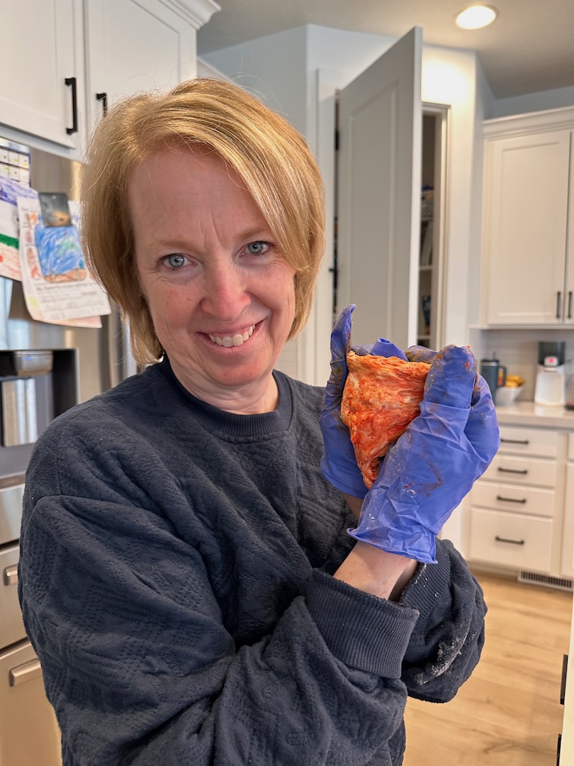 grandma holding a ball of orange dough for making rainbow bagels